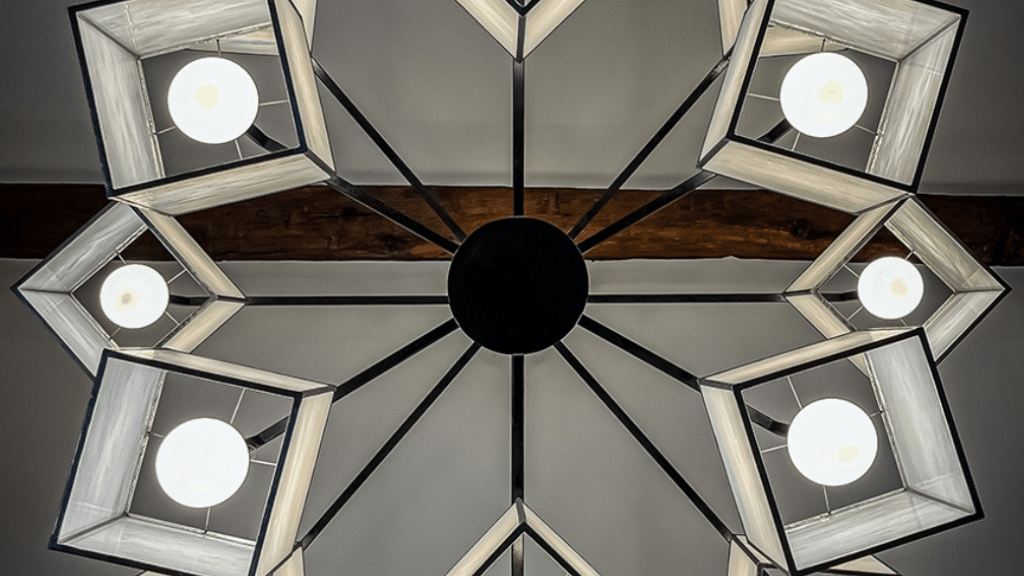 Lustre géométrique avec abat-jour carrés et ampoules LED, suspendu au plafond avec des poutres en bois apparentes