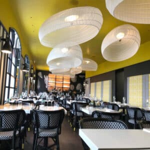 Vue large d’un restaurant avec luminaires en métal blanc et décor noir et jaune