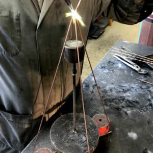 Atelier de soudure où un artisan façonne un cadre de luminaire en métal