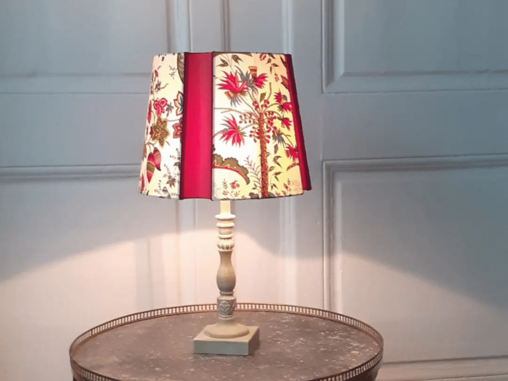 Lampe de table au style vintage avec un abat jour en tissu imprimé floral et rouge, posée sur une table en métal dans un intérieur élégant