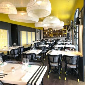 Salle de restaurant avec plafond jaune et luminaires suspendus en métal blanc