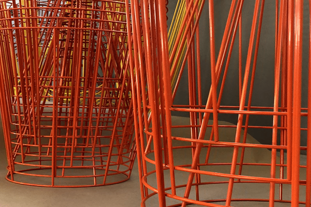 Structures métalliques cylindriques peintes en orange et jaune, utilisées pour la fabrication de luminaires