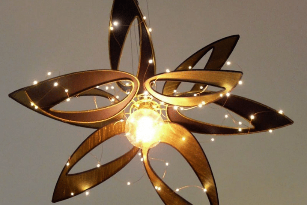 Suspension lumineuse en forme de fleur, composée de pétales ajourés en bois et ornée de guirlandes LED scintillantes autour d’une ampoule centrale