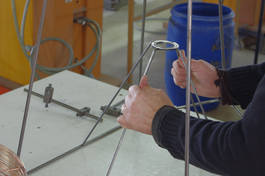 Artisan assemblant une structure métallique pour un luminaire sur un plan de travail