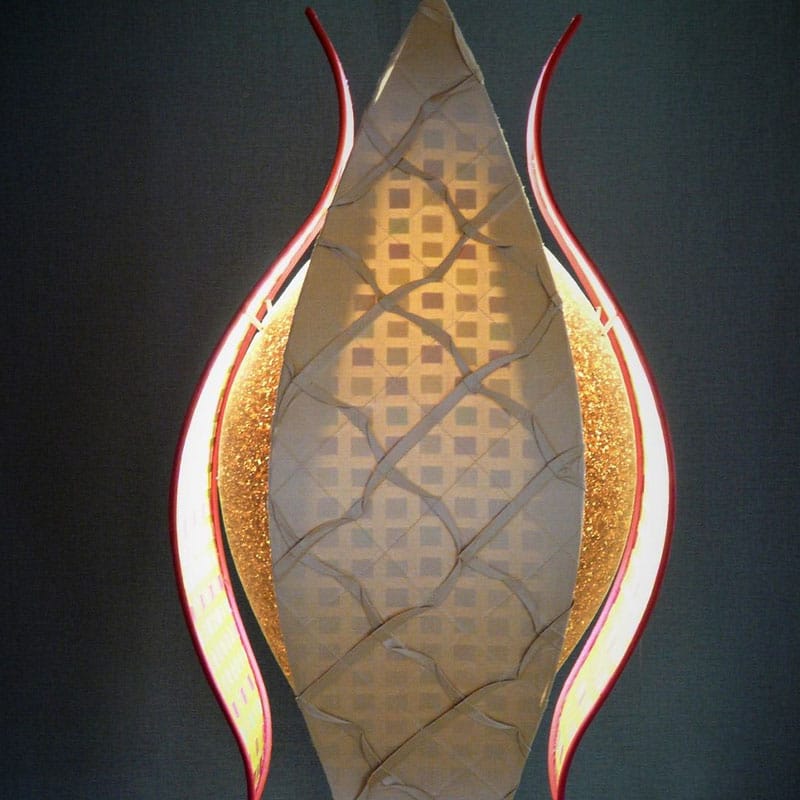 Luminaire sculptural en forme de flamme, avec structure en métal rouge et abat-jour texturé illuminé