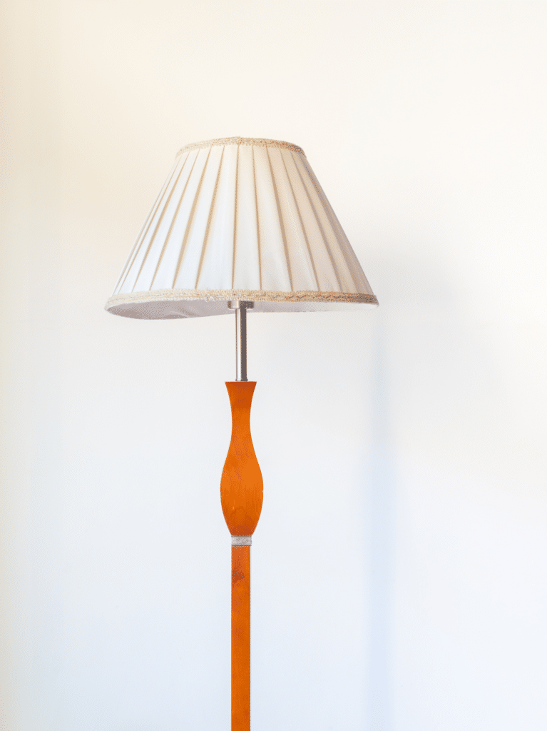 Lampadaire en bois avec abat-jour plissé blanc sur fond blanc
