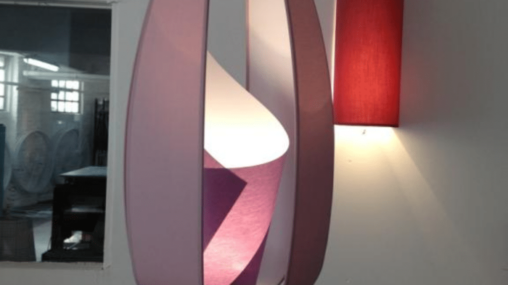 Luminaire sculptural aux formes courbes et aériennes, combinant des panneaux translucides violets et blancs pour un éclairage doux et diffus