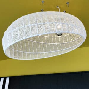 Gros plan sur un luminaire suspendu en métal blanc avec structure grillagée