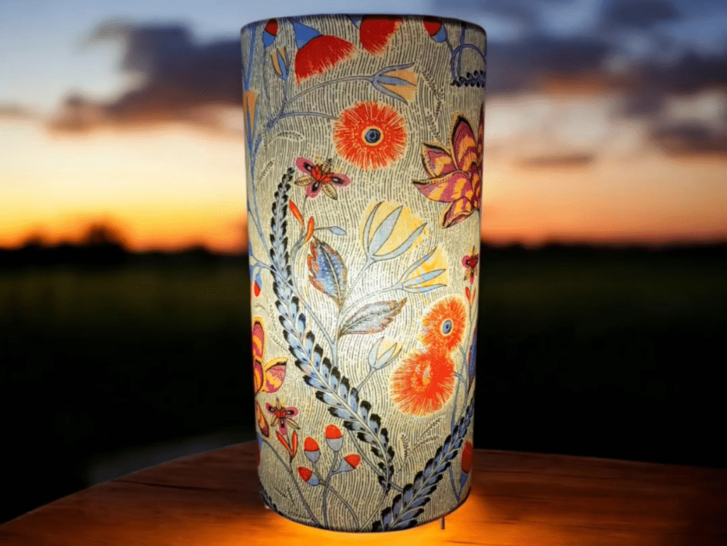 Lampe cylindrique en tissu floral illuminée au crépuscule, ambiance poétique