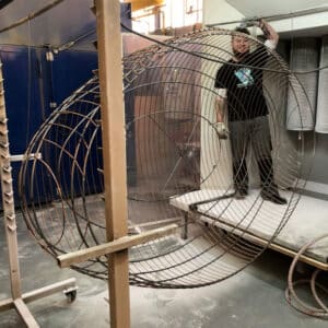 Artisan tenant une structure métallique en cours de fabrication pour un luminaire